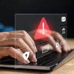 Hands typing on keyboard with a warning sign over it